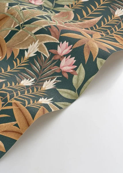 A close-up of a tropical botanical patterned surface, likely wallpaper or fabric, featuring pink flowers and tan leaves on a dark teal-green background, shown folded over on a white surface.